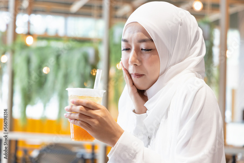 Muslim woman drinking cold beverage and feeling tooth decay or tooth sensitivity pain photo