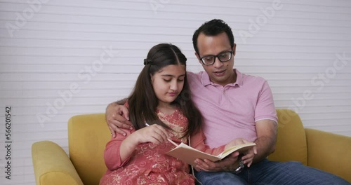 Indian father teaching home work his daughter