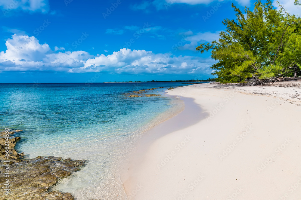 A view along a sandy beach with reef offshore on the island of Eleuthera, Bahamas on a bright sunny day