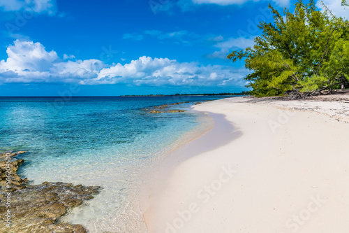 Fototapeta Naklejka Na Ścianę i Meble -  A view along a sandy beach with reef offshore on the island of Eleuthera, Bahamas on a bright sunny day