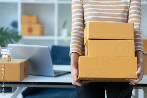 Portrait of Asian young woman SME working with a box at home the workplace.start-up small business owner, small business entrepreneur SME or freelance business online and delivery concept. © Wasan