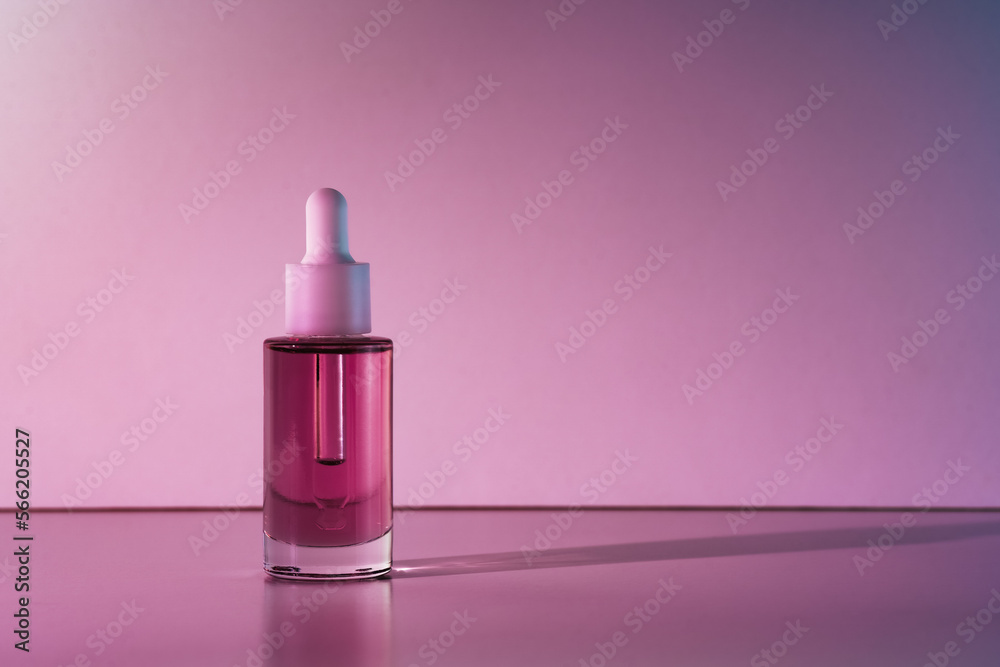 Pink face oil in glass bottle with white pipette dropper cap. Body care cosmetics background with copy space dark mood Pink face oil in glass bottle with white pipette dropper cap. Body care cosmetics background with copy space dark mood