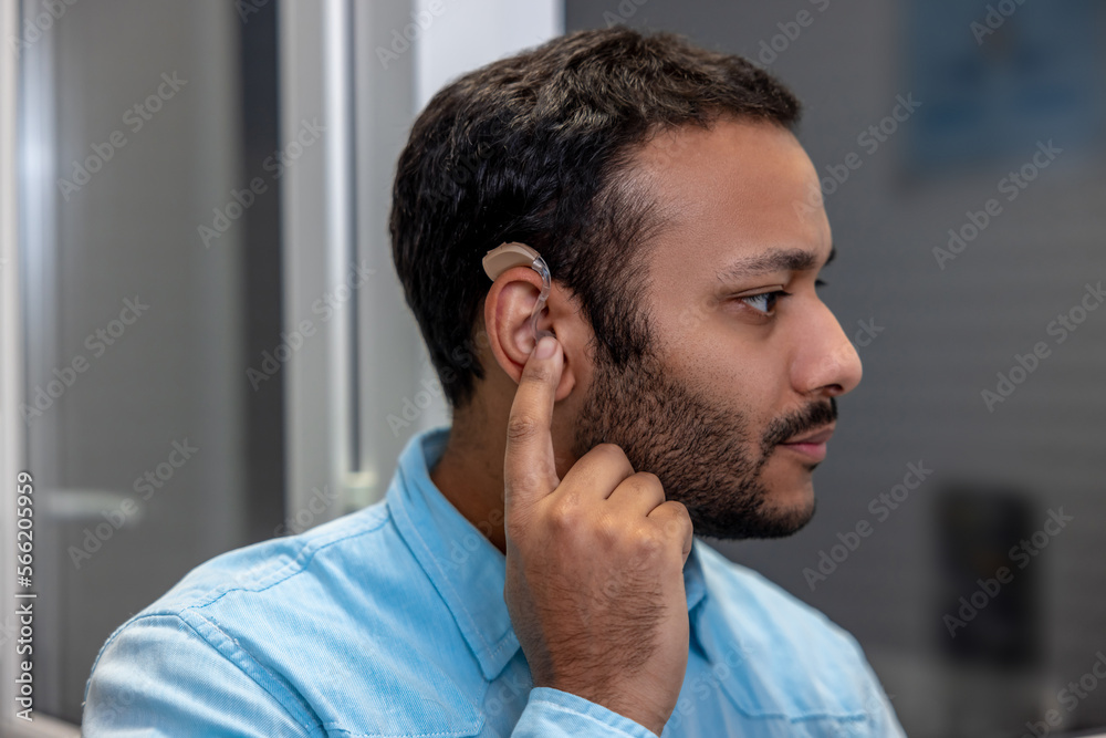 Obraz premium Smiling young man holding a hearing aid