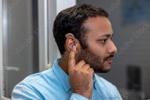 Smiling young man holding a hearing aid
