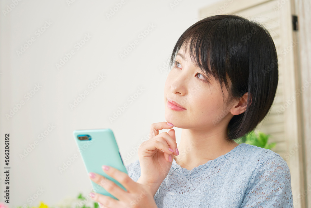 家でスマホ持って考える女性