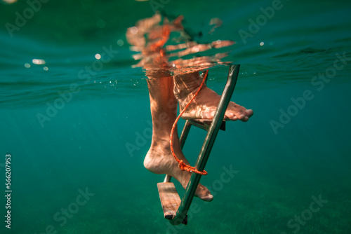 A man climbs down a ladder underwater off a boat near Utila Island, Honduras. photo