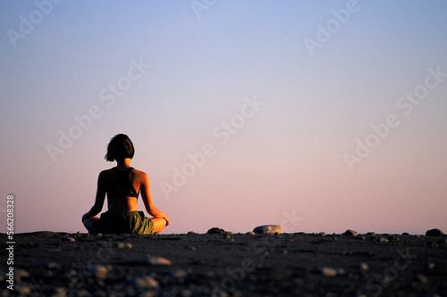 Woman meditating on the beach at sunset. photo