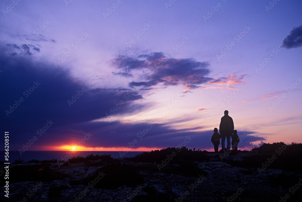 Father with children watching sunset on cliff. Father with children watching sunset on cliff.