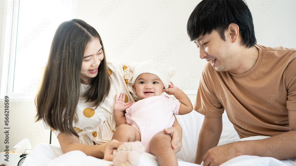 Smiling mother and father holding their newborn baby daughter at home. portrait of Asian family in bed room. Smiling mother and father holding their newborn baby daughter at home. portrait of Asian family in bed room.