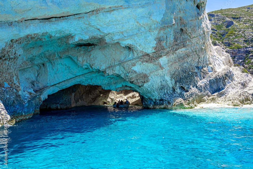 Tourists on an excursion boat explore the inside of a sea grotto flooded with sunlight, surrounded by turquoise waters, Zante, Zakynthos, Greece