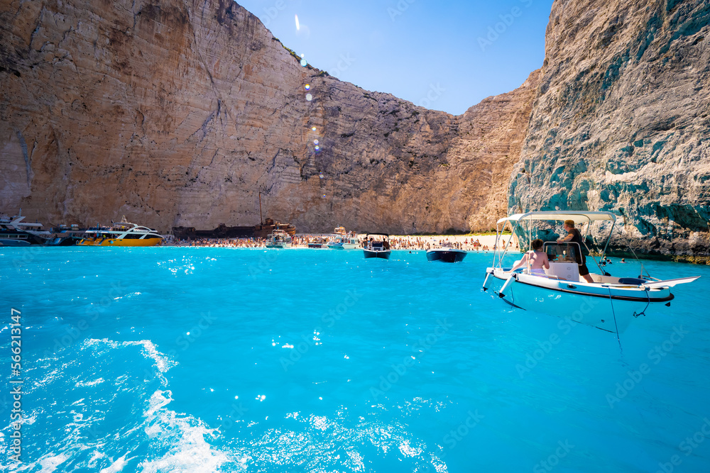 Beautiful view of boats taking tourists to the old rusty shipwreck stranded on Navagio beach on Zakynthos island in Greece, surrounded by high cliffs