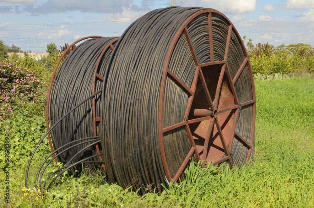 Cable drums with fiber optic cable.Technologies poly underground conduit in a green field, on a farm Cable drums with fiber optic cable.Technologies poly underground conduit in a green field, on a farm