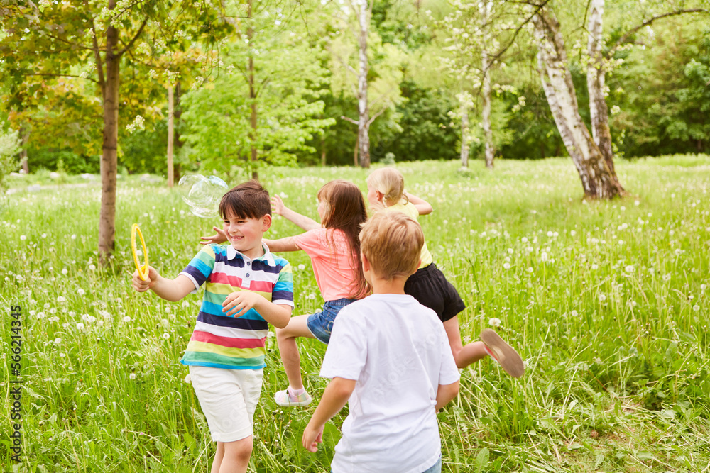 Obraz premium Multiracial children playing with soap bubbles in grass