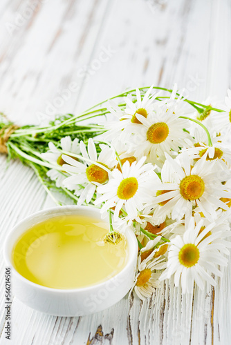 aromatic chamomile essential oil on a white wooden rustic background