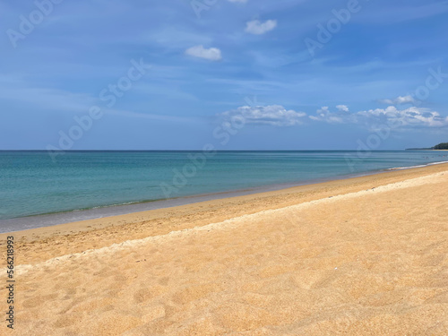 Сoastline stretches beautifully into the distance towards the horizon at an angle. Empty shore. Pure yellow sand. Blue sky with clouds. Smooth surface of water, calm sea. Ocean space. Tropical beach. 