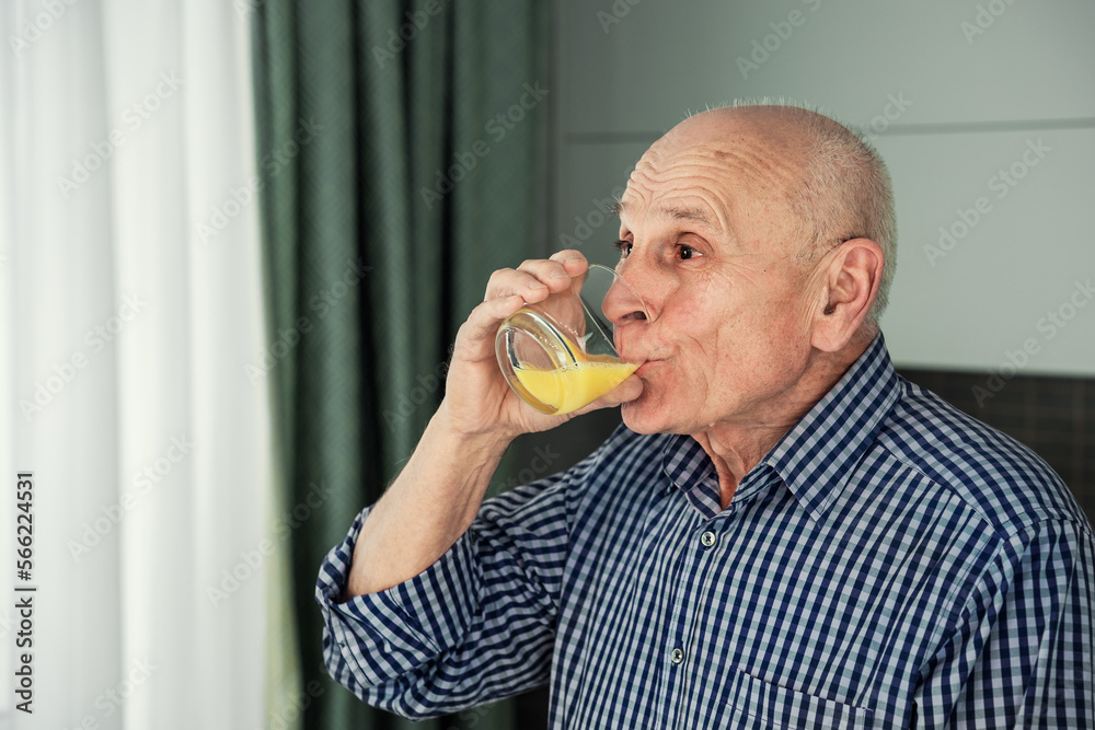 Old man drinking orange juice from glass close side view. Old man drinking orange juice from glass close side view.