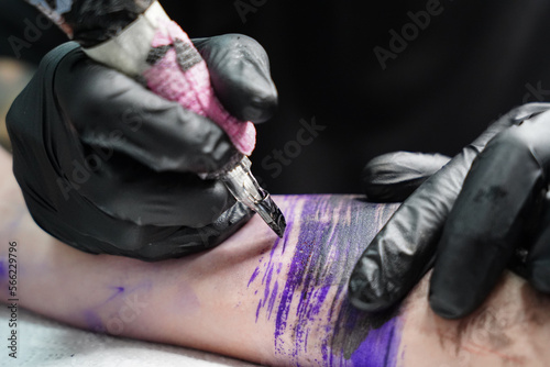 Close-up of a woman making a tattoo to arm. Alternative art