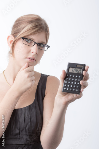 Young woman is using a calculator in front a bright white background and looks worried