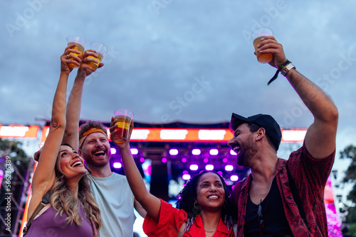 Excited friends cheering with beer at concert photo