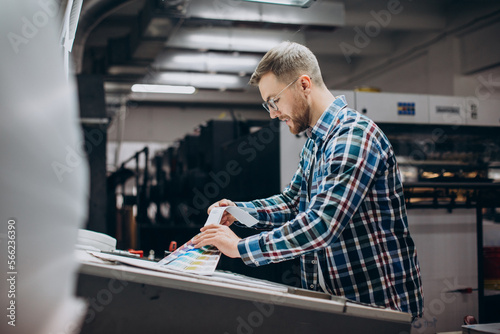 Man working in printing house with paper and paints photo