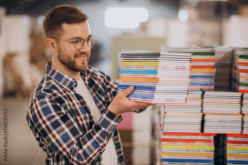 Man working in printing house with paper and paints photo