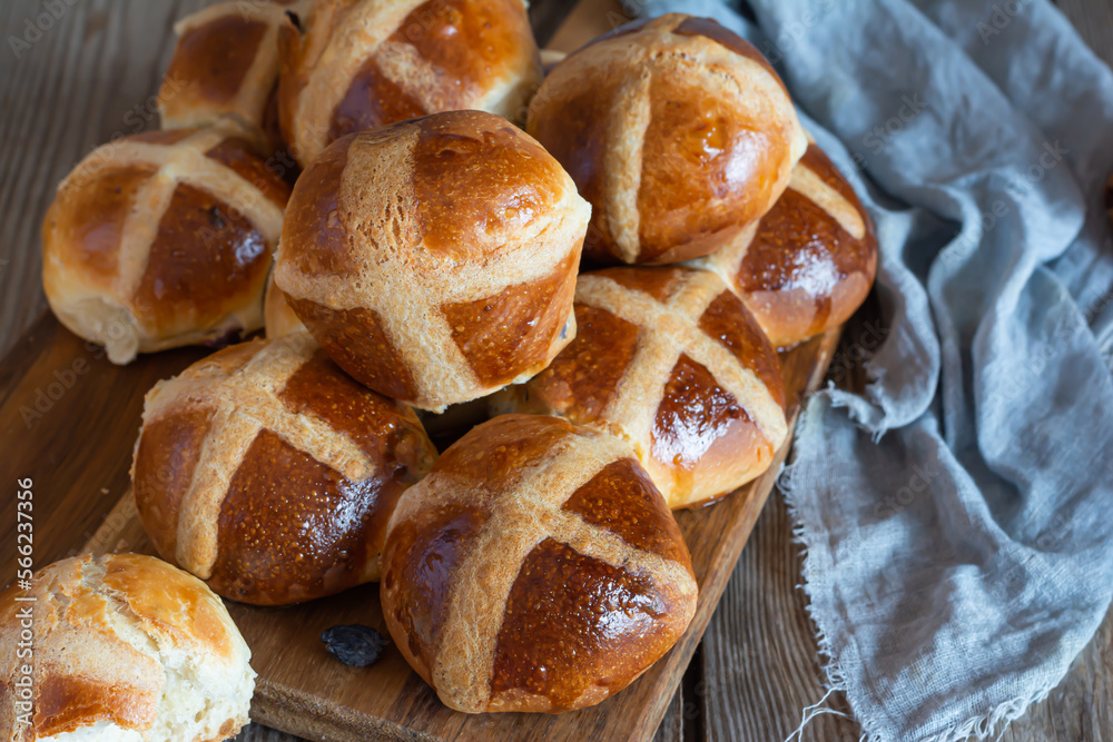 Hot cross buns with raisins, traditional English (European) pastry for Easter week on a wooden board. Delicious sweet pastries.