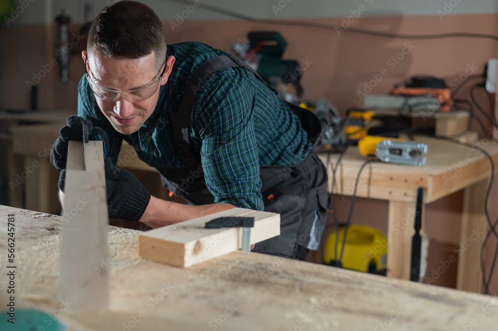 Carpenter measures a wooden board while working in a workshop. Carpenter measures a wooden board while working in a workshop.