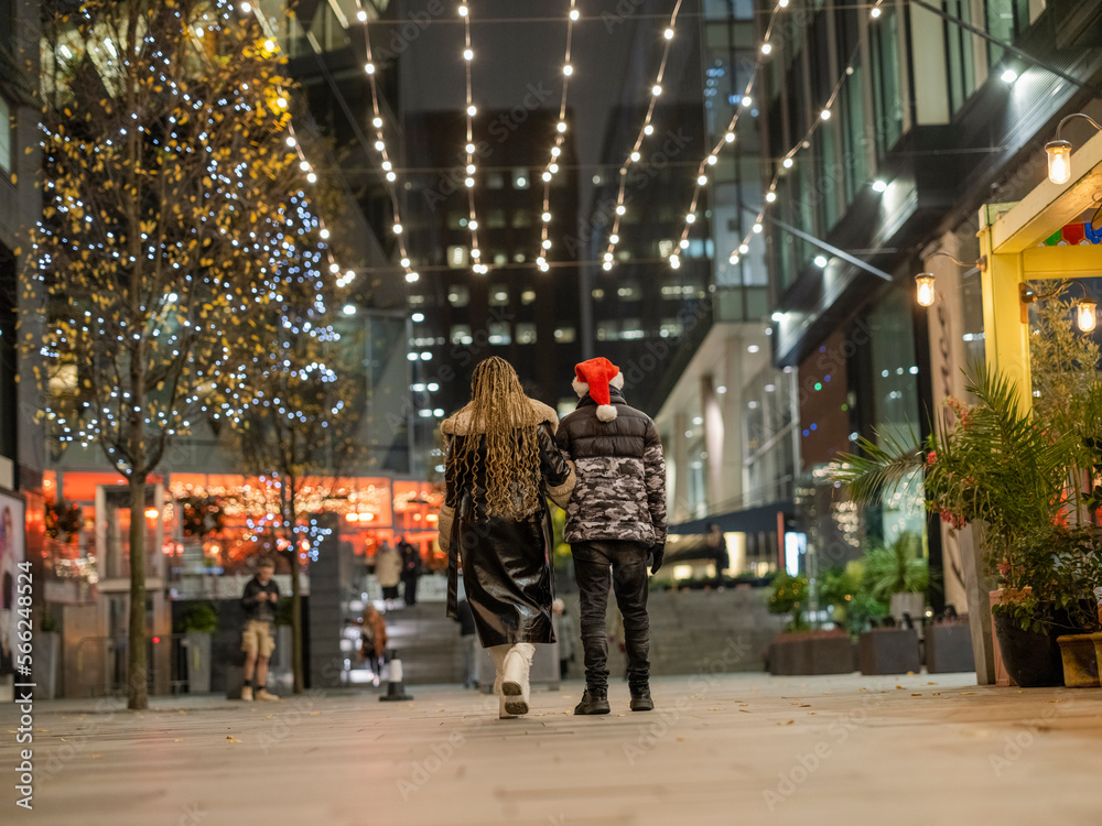 Young couple walking under Christmas lights