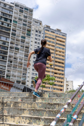 Brazil, Sao Paulo, Rear view of woman exercising on steps in city