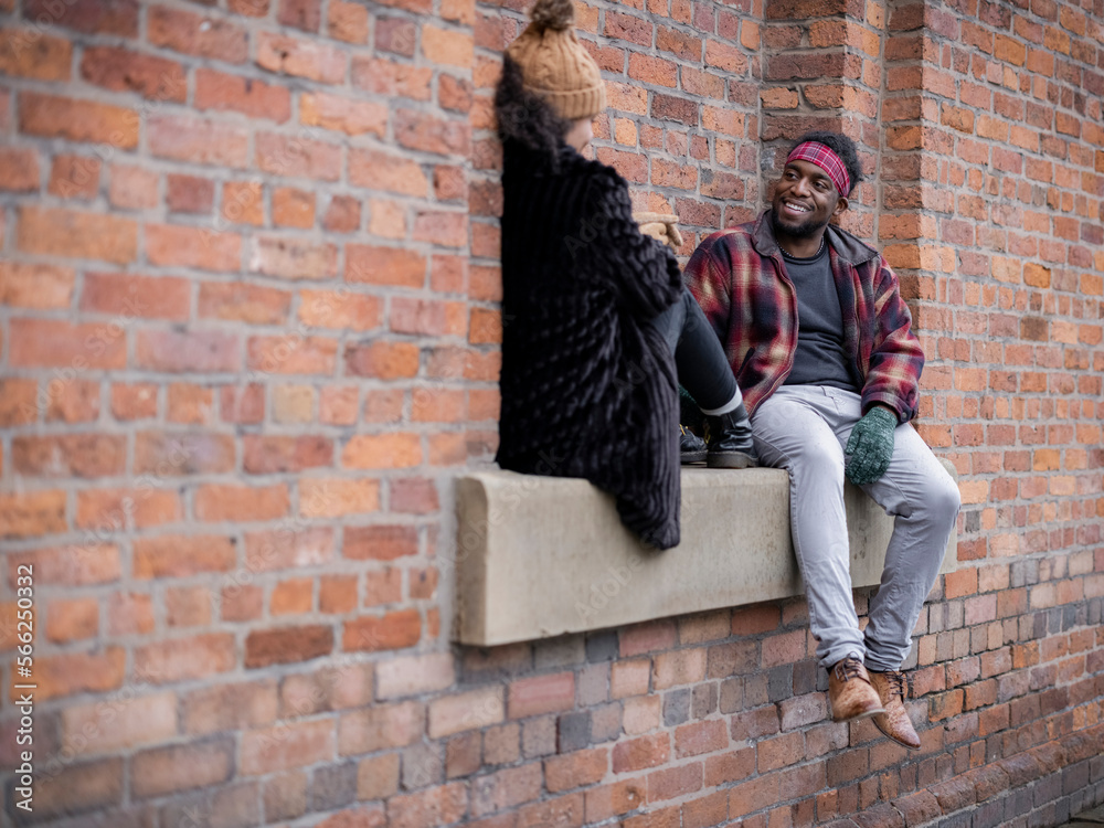 Couple sitting in brick wall niche Couple sitting in brick wall niche