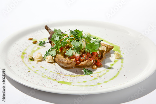 Baked eggplant with cheese on white table with harsh shadows. Aesthetic italian food - baked aubergine on white plate. Stuffed eggplant in minimal style. Stuffed aubergine in vegan menu.