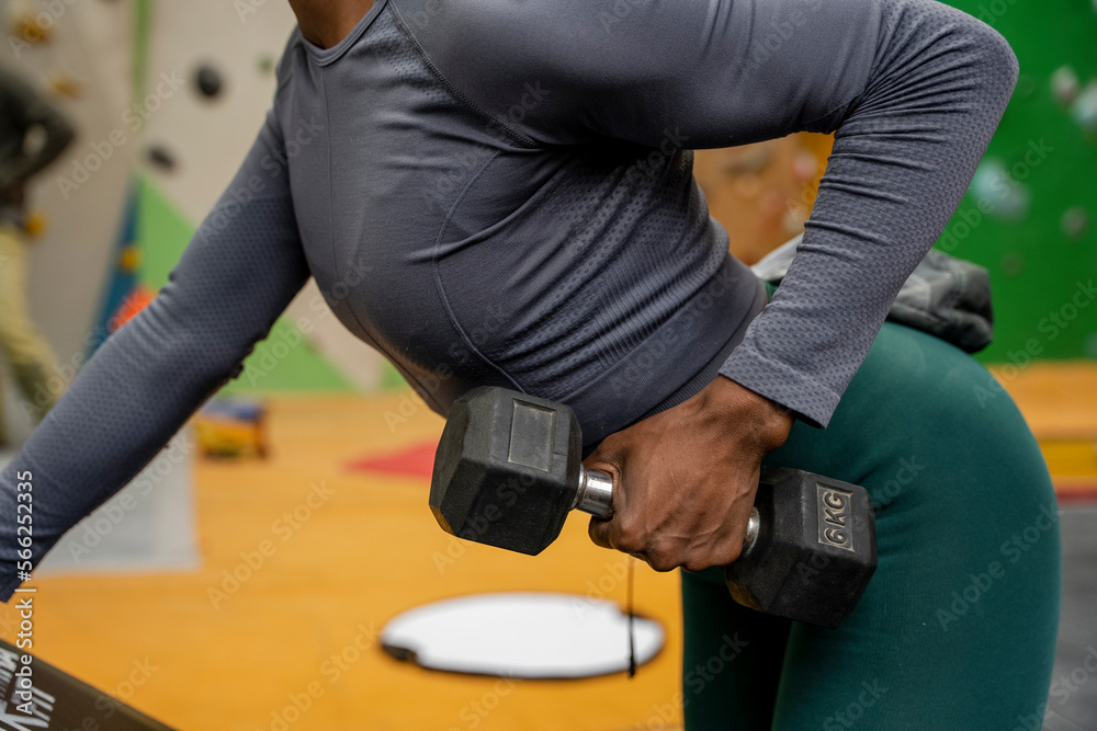 Mid section of woman exercising with dumbbells at gym Mid section of woman exercising with dumbbells at gym