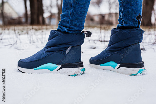 Winter puffy boots on female legs in winter on snow
