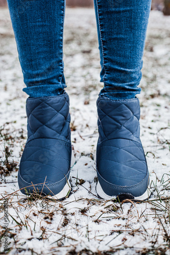 Winter puffy boots on female legs in winter on snow