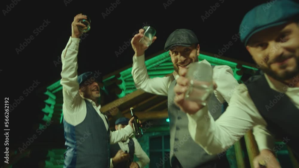 Group of young drunk men drinking alcohol , toasting , cheering , celebrating . Bachelor party with groom . Close up boys toasting on camera . Restaurant or house with led neon lights on background Group of young drunk men drinking alcohol , toasting , cheering , celebrating . Bachelor party with groom . Close up boys toasting on camera . Restaurant or house with led neon lights on background