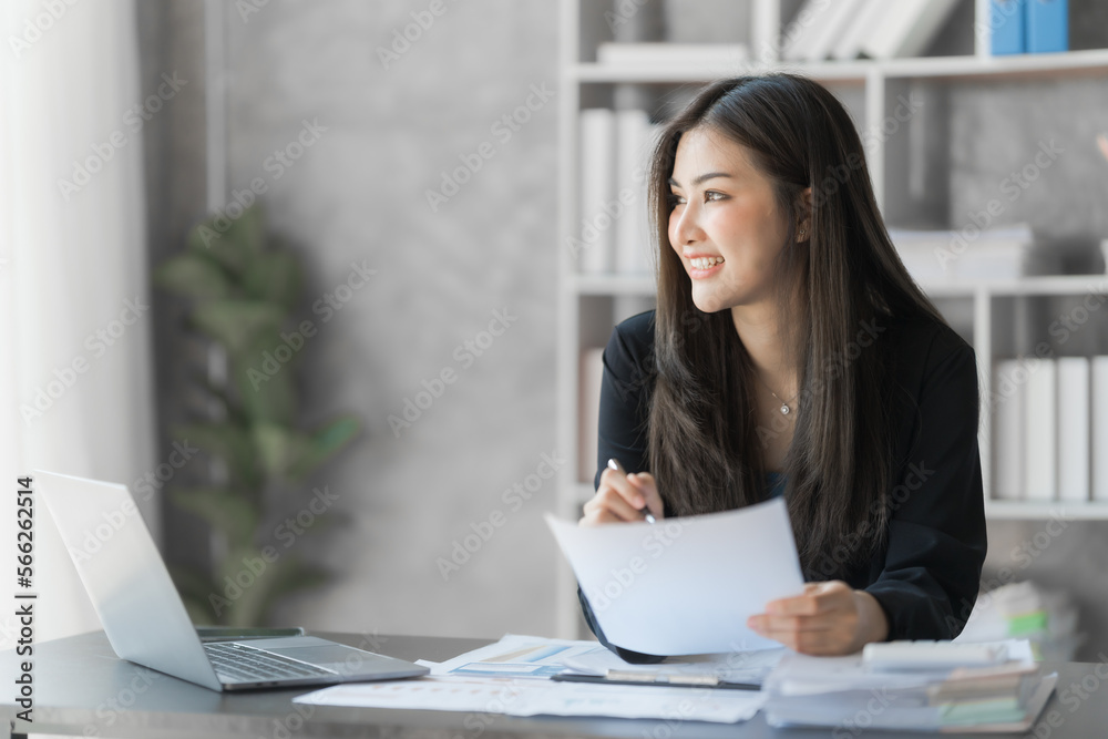 Beautiful Asian female bookkeeper doing online accounting with laptop in private accounting office, balance sheet and stock market statistics. Beautiful Asian female bookkeeper doing online accounting with laptop in private accounting office, balance sheet and stock market statistics.