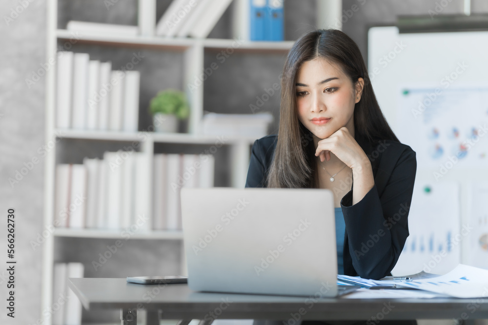 Beautiful Asian female bookkeeper doing online accounting with laptop in private accounting office, balance sheet and stock market statistics. Beautiful Asian female bookkeeper doing online accounting with laptop in private accounting office, balance sheet and stock market statistics.
