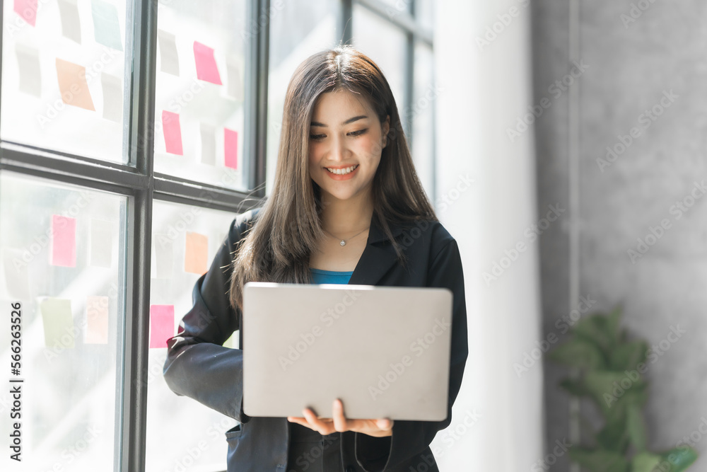 Using laptop, Pretty asia business woman bookkeeper brainstorming and working in modern office workplace with sticky notes or post it at windows.
