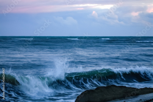 Dark sea waves in a blur against the background of the sunset sky. Worryingly.