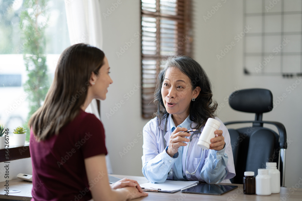 Senoir female doctor explaining bottle of medicine to her young patient.