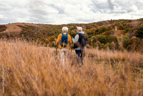 Active senior couple with backpacks hiking together in nature on autumn day. © Zoran Zeremski