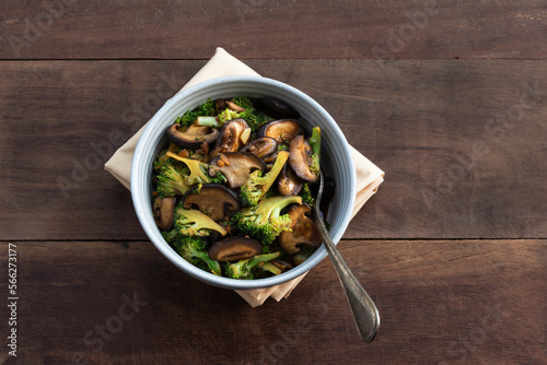 Healthy vegetarian food stir fried broccoli mushroom in bowl on wood table.