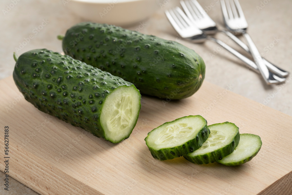 Whole and sliced fresh healthy snack cucumber, Marketmore, close up on a cuttingboard  
