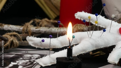 Seance with voodoo doll and curse. Red candles, black background, scary atmosphere in the frame.