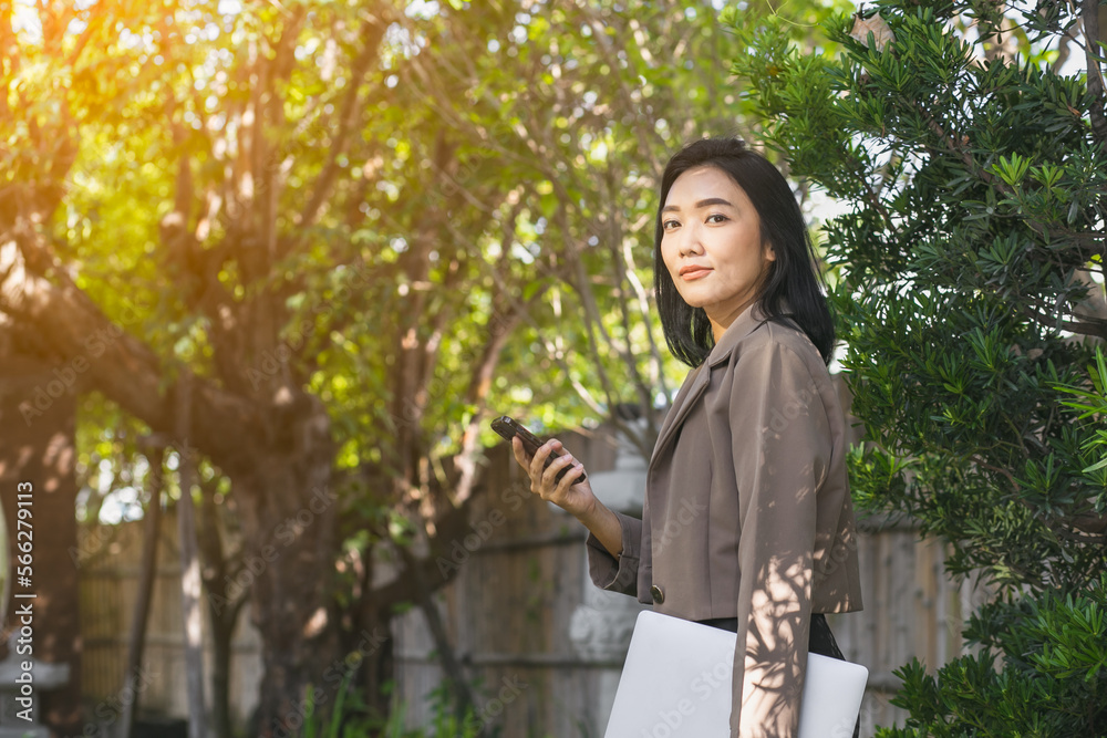 Young beautiful Asian woman working with smartphone and laptop, She used the internet and shopped online in the garden, freelancer working businesswoman lifestyle concept Young beautiful Asian woman working with smartphone and laptop, She used the internet and shopped online in the garden, freelancer working businesswoman lifestyle concept