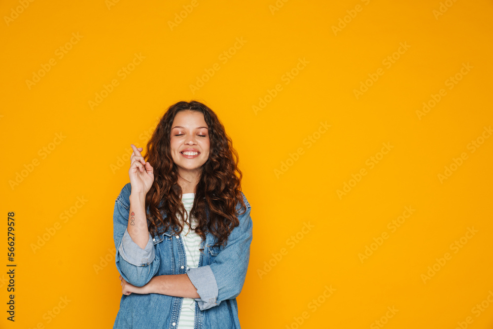 Young curly girl doing hope gesture with crossed fingers isolated Young curly girl doing hope gesture with crossed fingers isolated