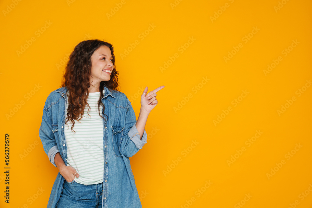 Young girl pointing finger at copy space isolated over yellow background Young girl pointing finger at copy space isolated over yellow background