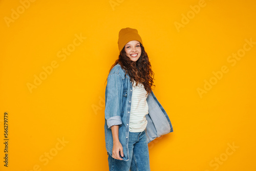 Cheerful young girl standing isolated over yellow background © Drobot Dean