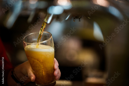 Close up of glass with on tap drink pouring into glass at pub