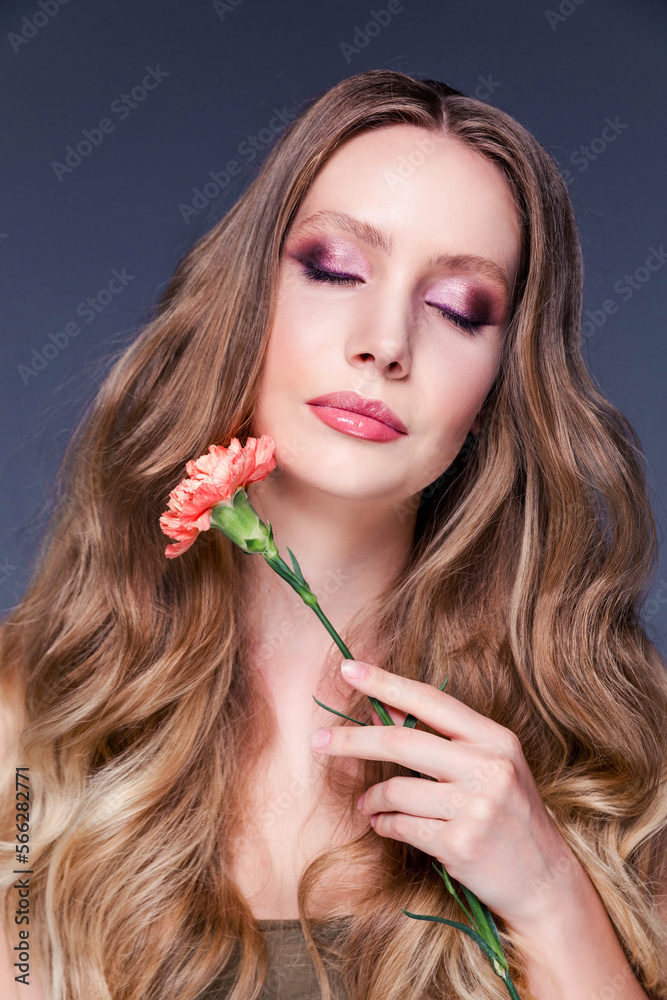 Obraz premium Beauty portrait of a girl. A beautiful woman touches her face with a carnation flower. Facial treatments. Cosmetology, skin care and spa.